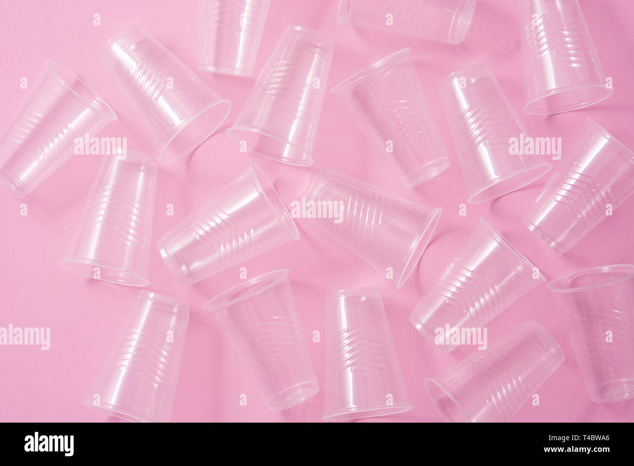 Disposable waste plastic glasses on pink background. Top view Stock Photo