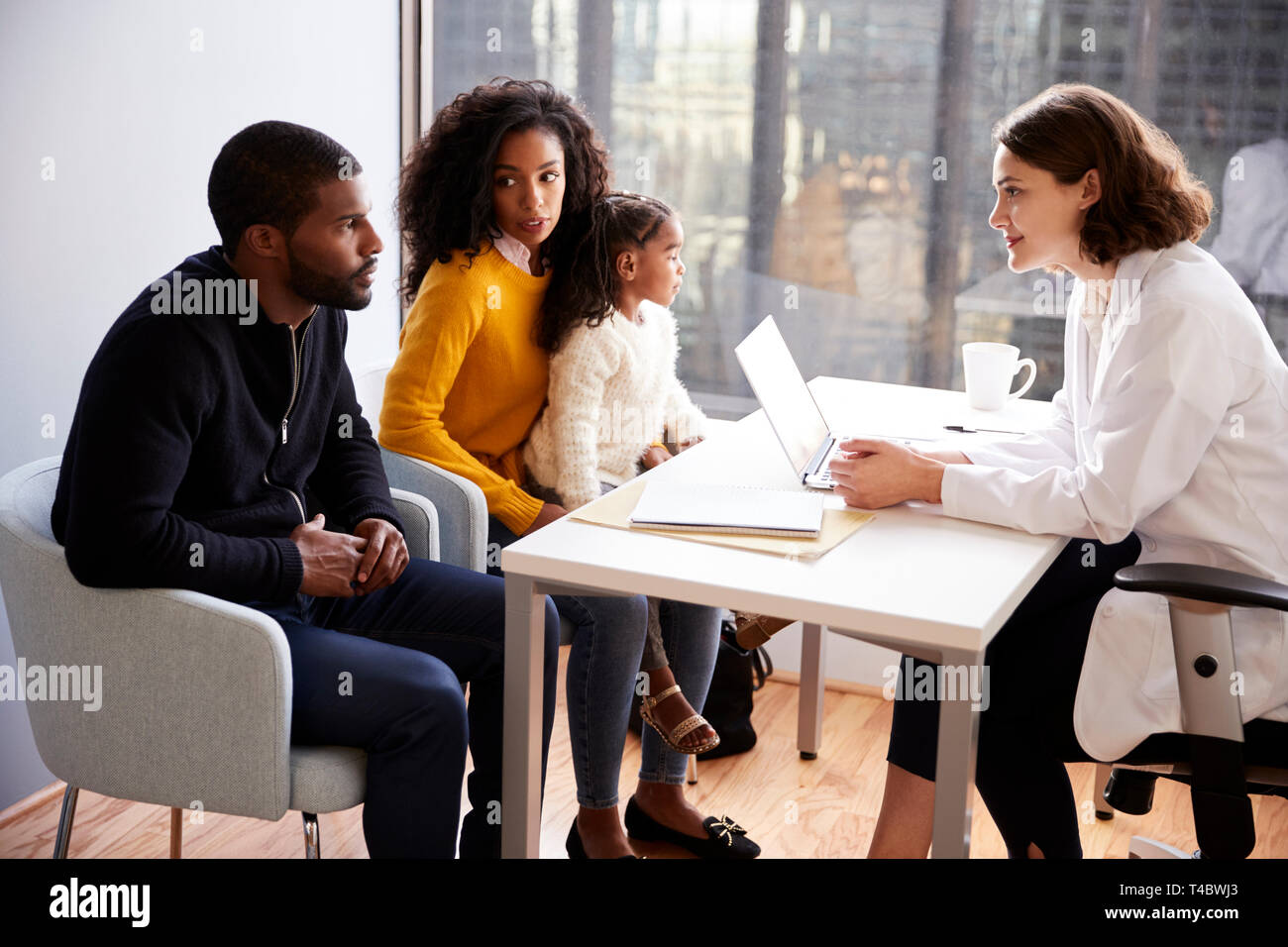 Family Having Consultation With Female Pediatrician In Hospital Office Stock Photo
