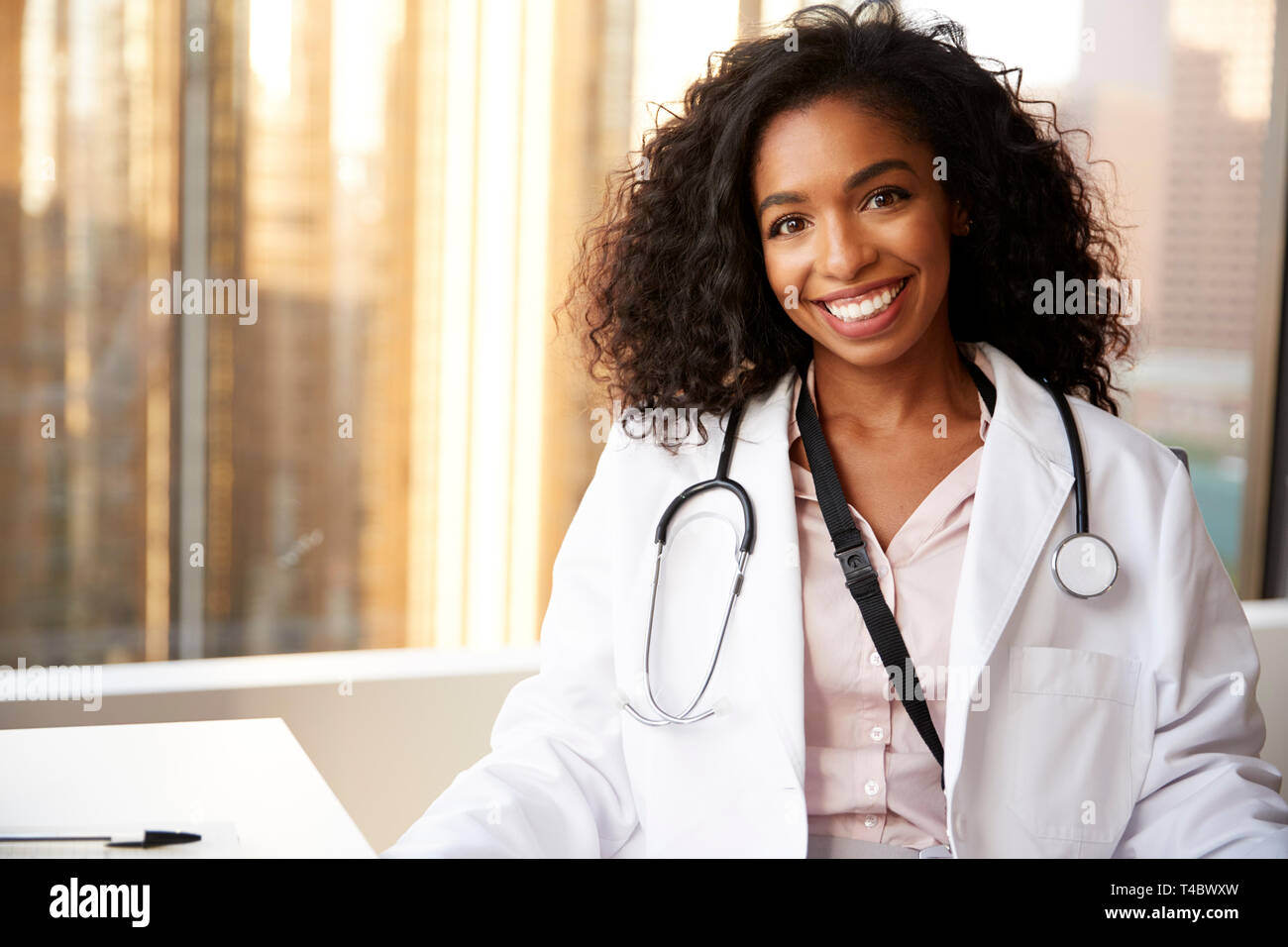Portrait Of Smiling Female Doctor Wearing White Coat With Stethoscope In Hospital Office Stock