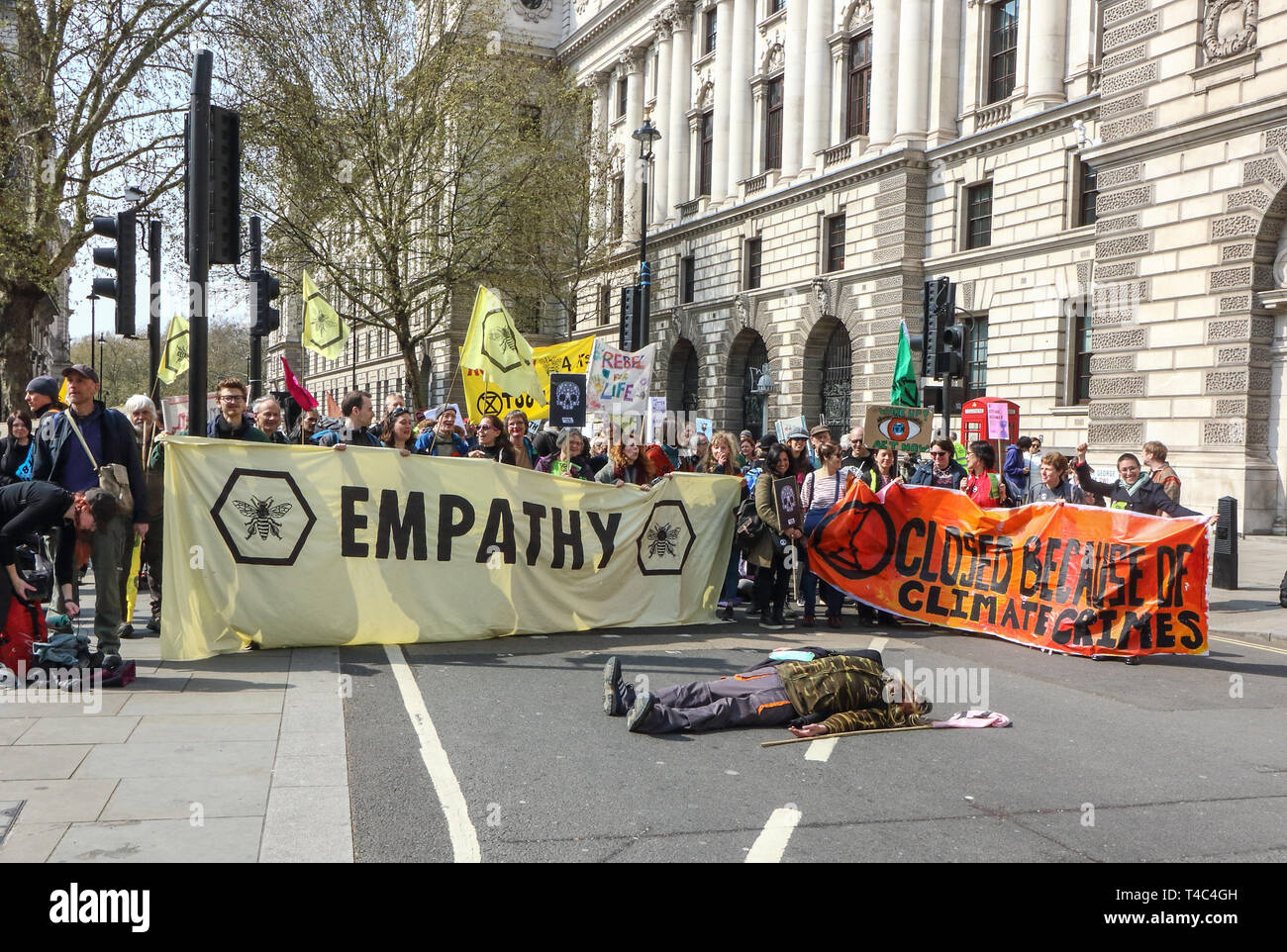 London, UK. 15th Apr, 2019. Protesters seen holding two large banner with a man performing a dead body in the middle of the road during the Extinction Rebellion demonstration in London. Extinction Rebellion protesters bring London to a standstill. The protesters lined up across the exits to Parliament Square in Westminster, with some sitting in the road. The group plan to be blocking five of the city's busiest and most iconic locations in a non-violent, peaceful act of rebellion - for up to two weeks Credit: Keith Mayhew/SOPA Images/ZUMA Wire/Alamy Live News Stock Photo
