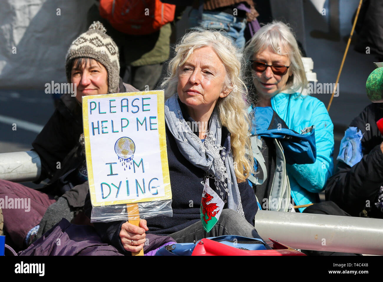 An environmental activist is seen holding a placard saying please help me I'm dying during the protest. Activist protest at the Parliament Square demanding for urgent Government action on climate change, the protest was organised by Extinction Rebellion. Stock Photo