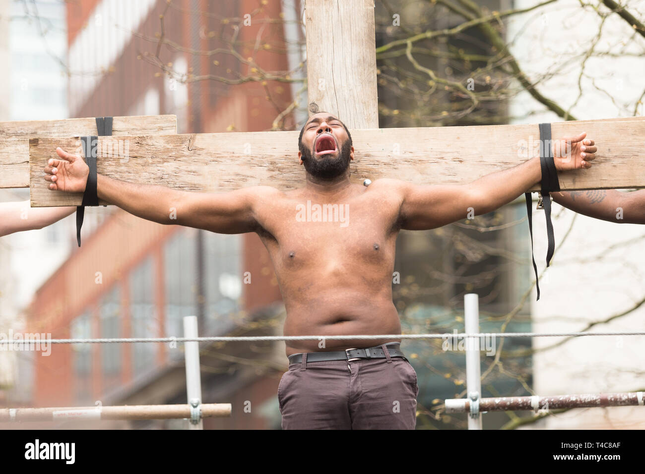 Birmingham, UK. 16th April, 2019. A contemporary Christ-figure is crucified. A diverse team of one hundred community actors, musicians and stewards alongside Saltine Theatre Company re-tell the Easter story in a live procession through Birmingham city centre. The procession finishes up at St. Philip’s Cathedral  Peter Lopeman/Alamy Live News Stock Photo
