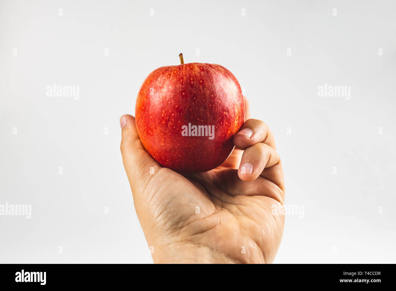 hand holding a red apple fruit against white background Stock Photo