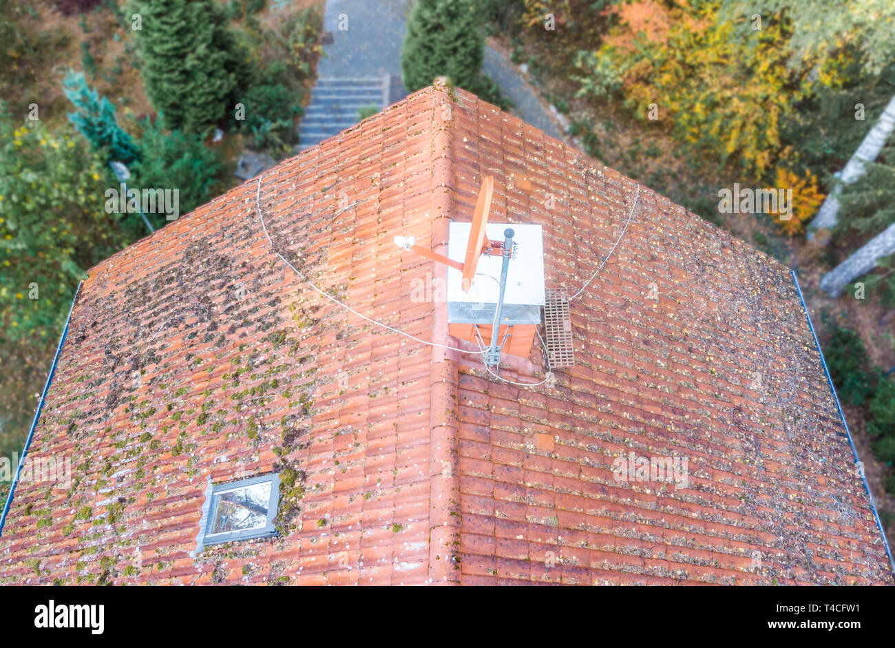 Inspection of the red tiled roof of a single-family house, inspection of the condition of the tiles on the roof of a detached house. Stock Photo