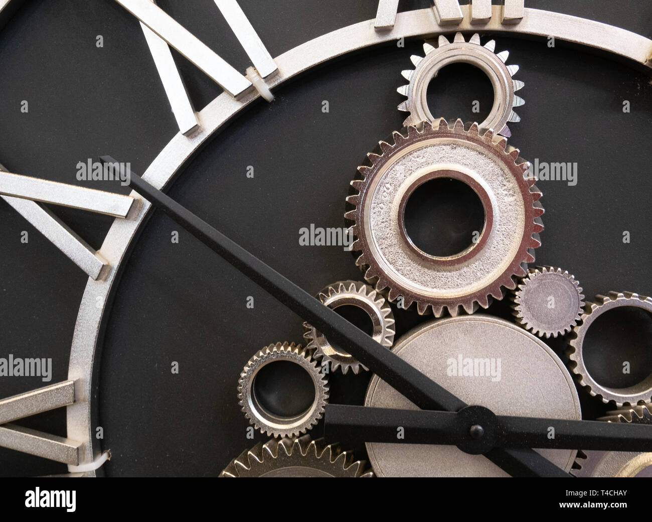 closeup of wall clock made of industrial gears cogwheels and metallic hour and minutes arrows Stock Photo