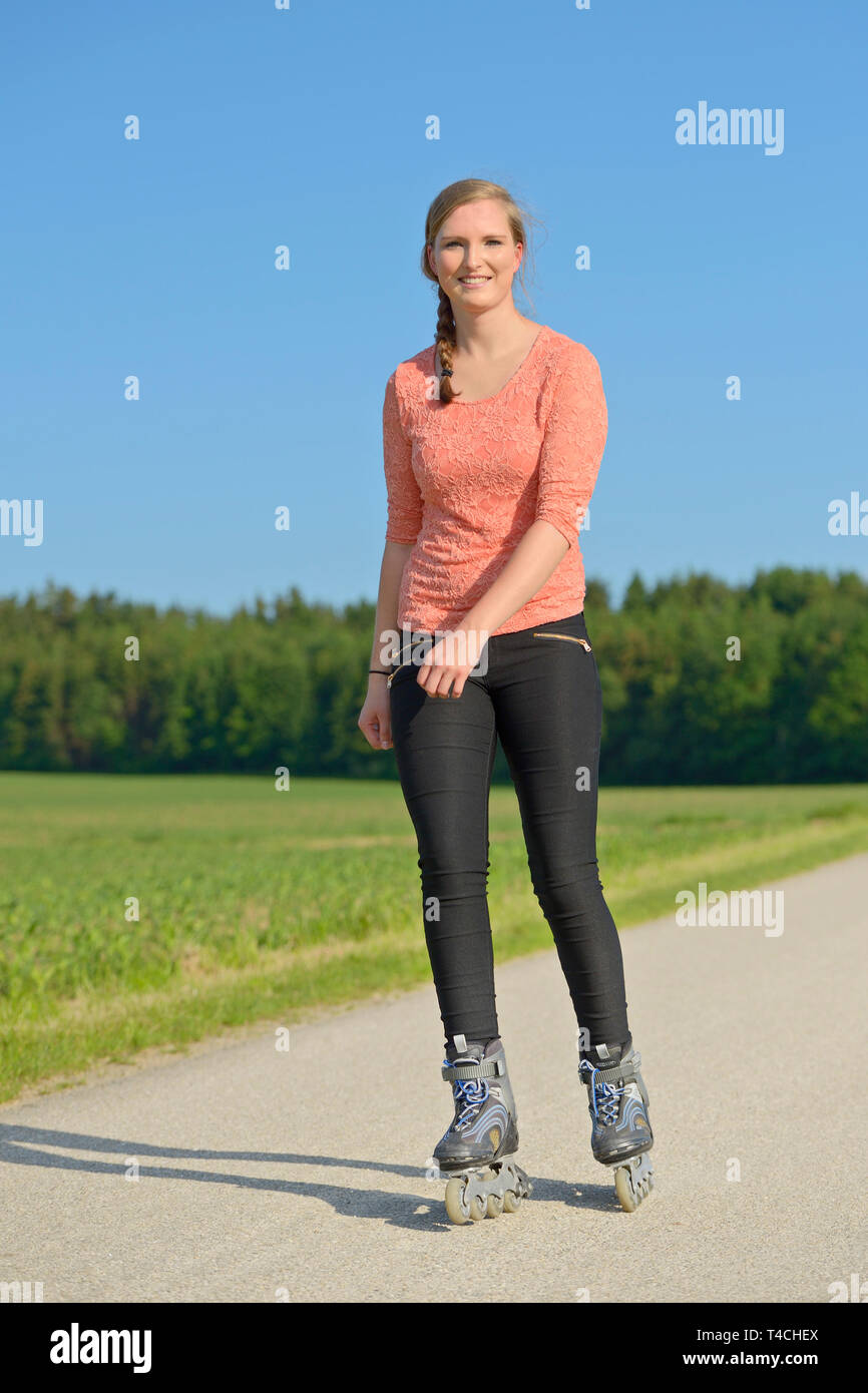 Young woman rollerblading on a small road. Stock Photo