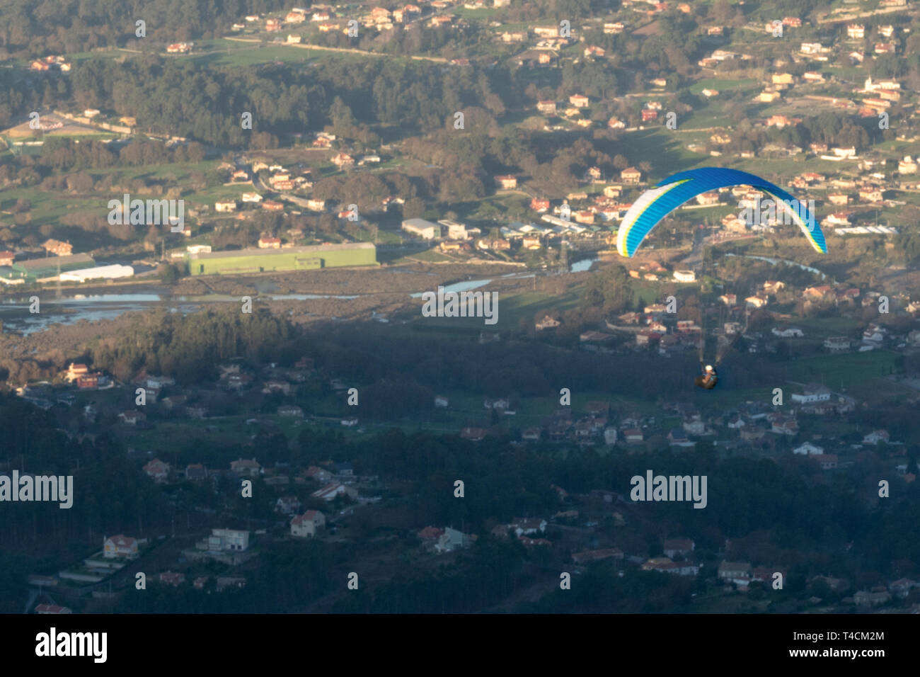 Person flying in paragliding over a small town Stock Photo