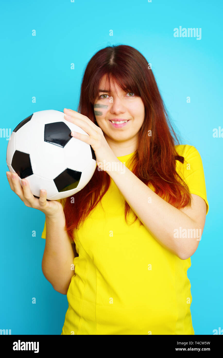 Woman is socccer fan in yellow t-shirt with soccer ball Stock Photo