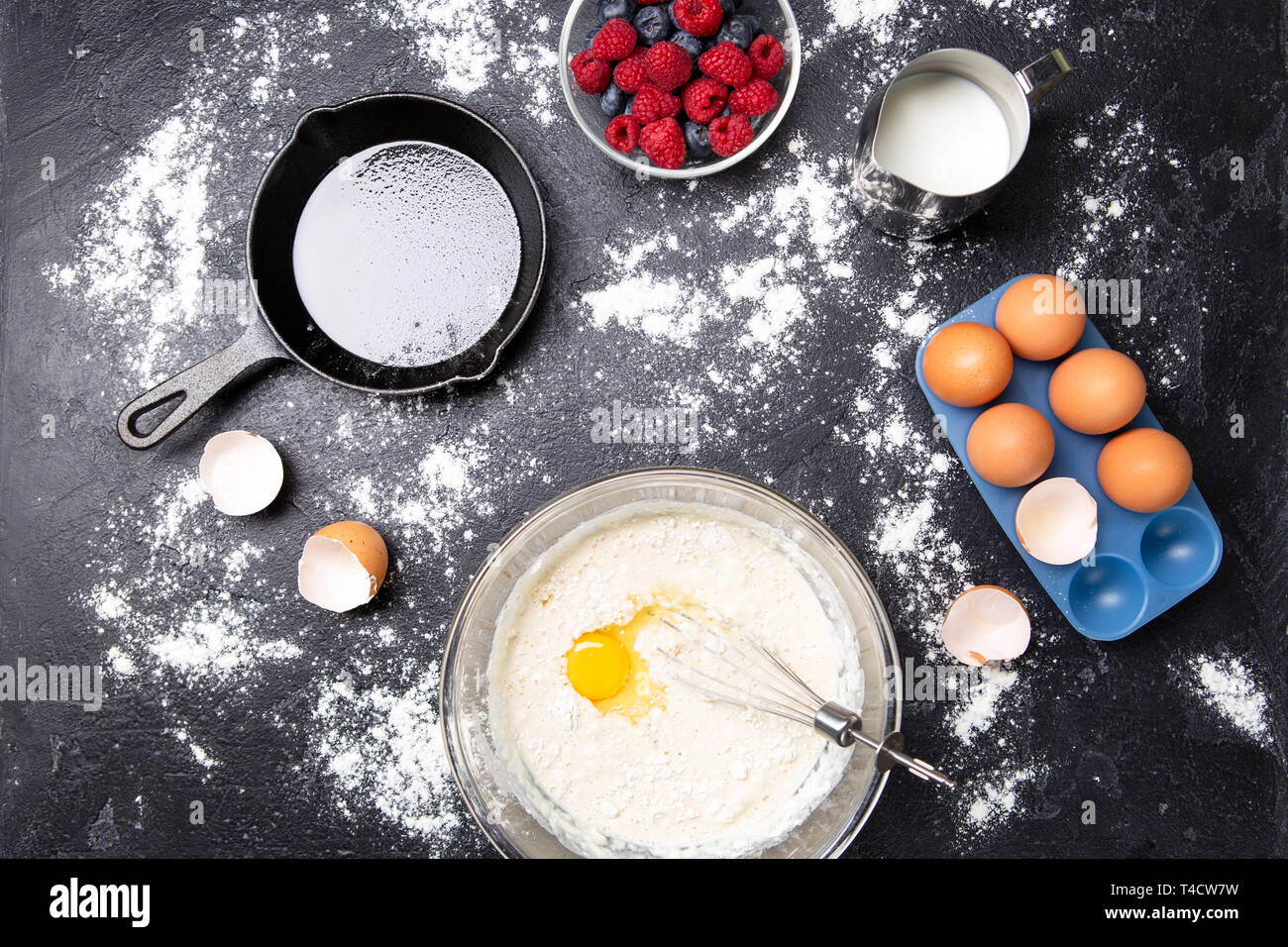 Photo on top of eggs, milk, flour, berries on black table. Stock Photo