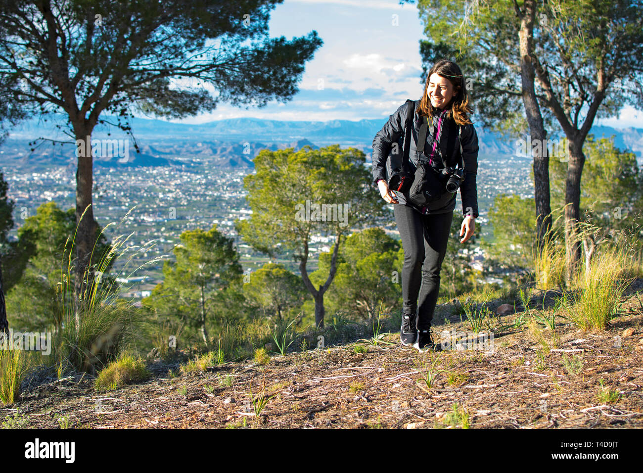 Murcia, Spain - April 9, 2019: cheerful young woman hiking and taking pictures with her reflex camera Stock Photo