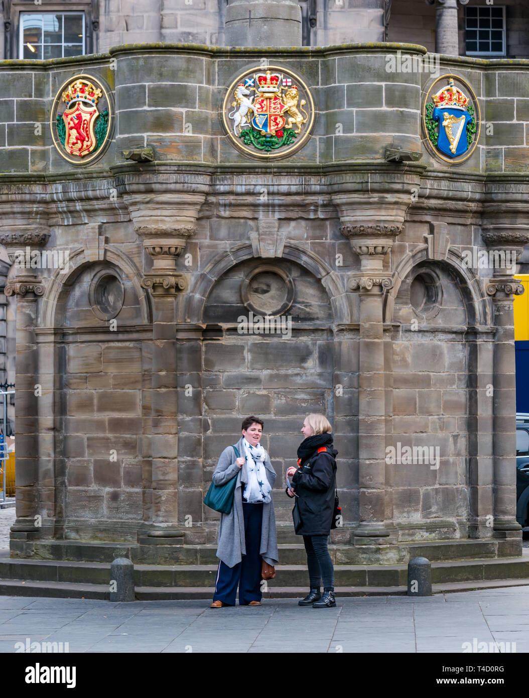 Women chatting next to the Mercat Cross, Parliament Square, Royal Mile Edinburgh, Scotland, UK Stock Photo