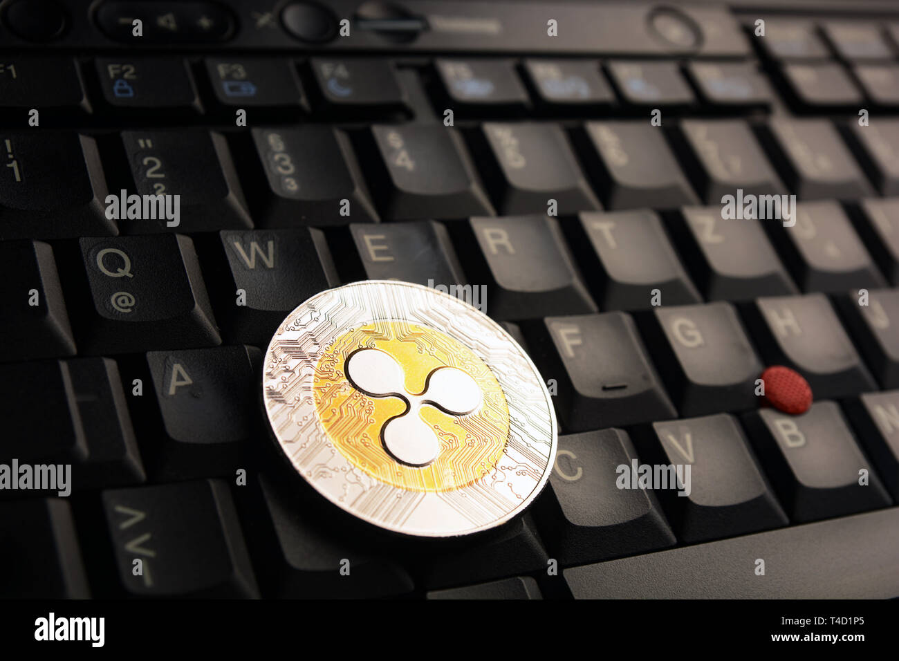 Golden Ripple XRP  coin on a black keyboard Stock Photo