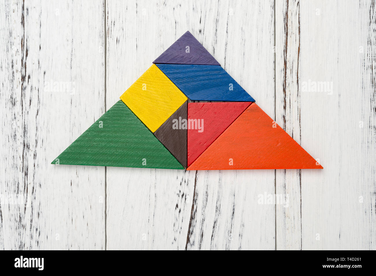 wooden tangram shaped as a triangle on white wood background Stock Photo -  Alamy