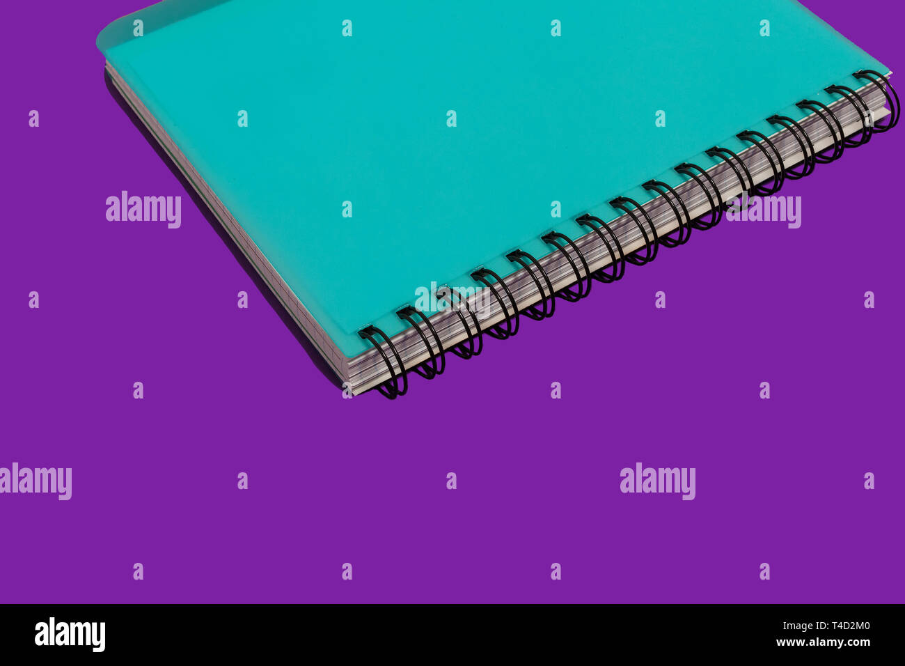 blue spiral notebook on a purple background Stock Photo