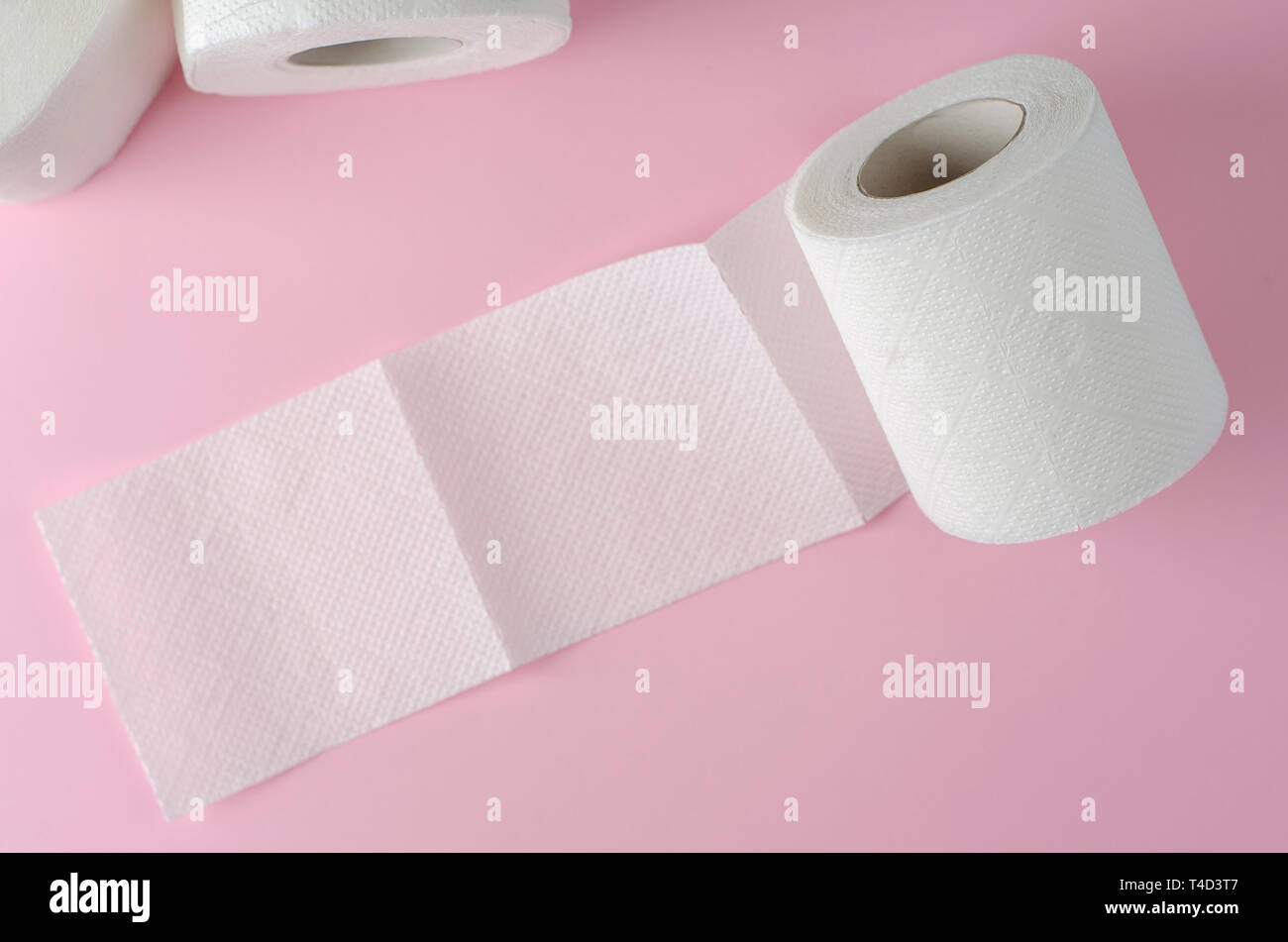Single white toilet paper roll on pastel pink background. Space for