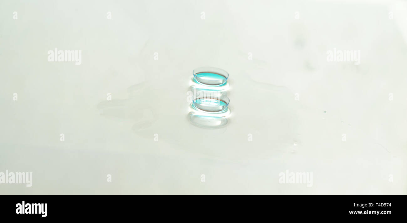 Panorama of Two contact lenses on white glass background.Focus on front lense. Stock Photo
