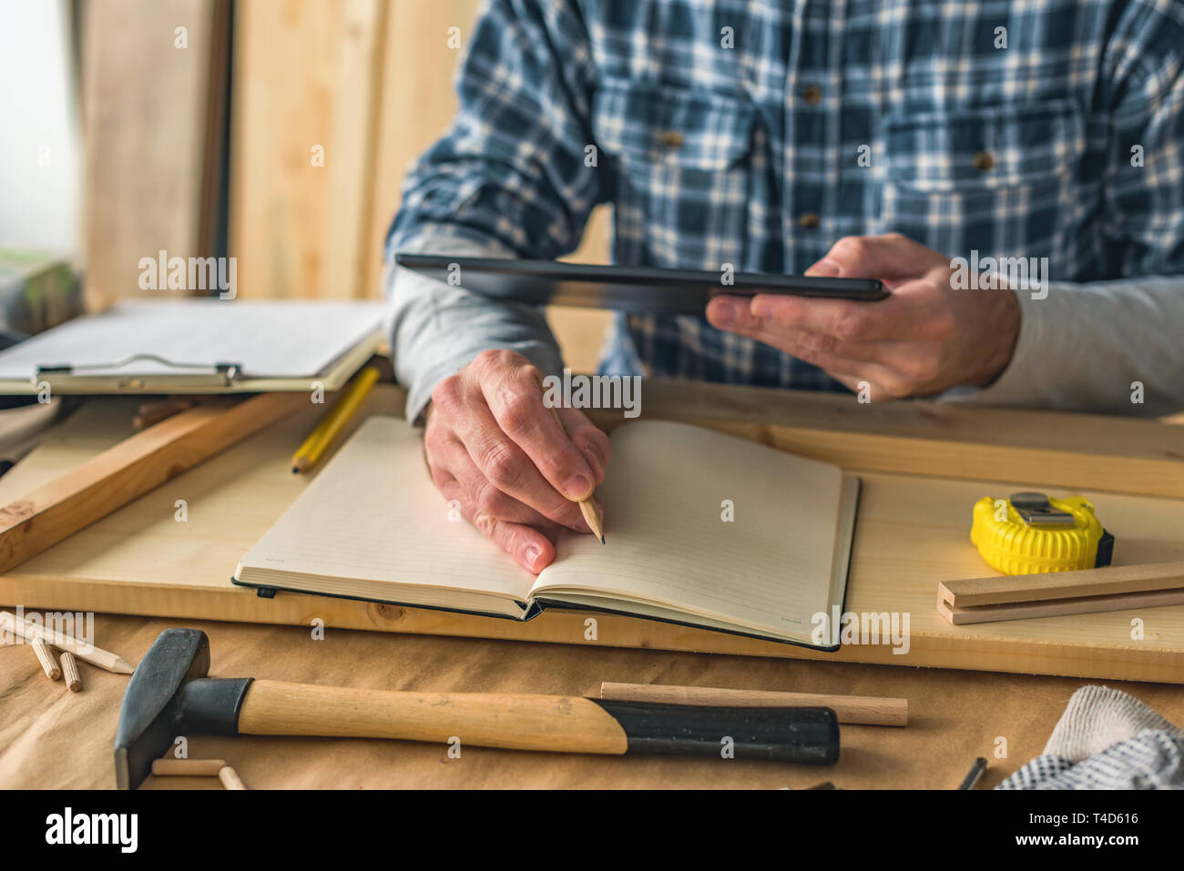 Carpenter using digital tablet to complete project to do list in small business woodwork workshop Stock Photo