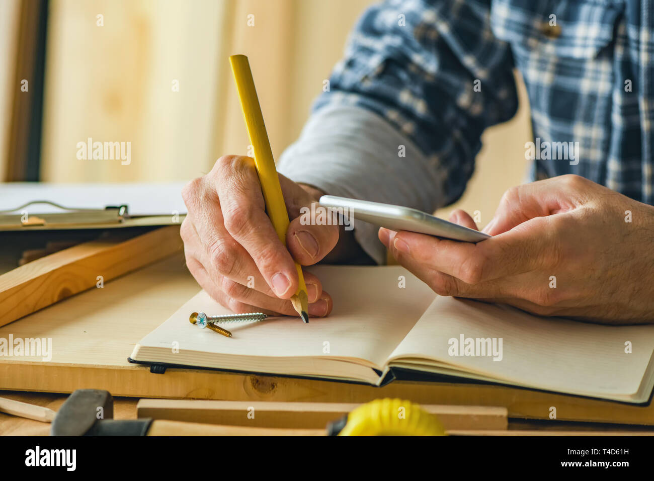 Carpenter writing project notes in small business woodwork workshop Stock Photo