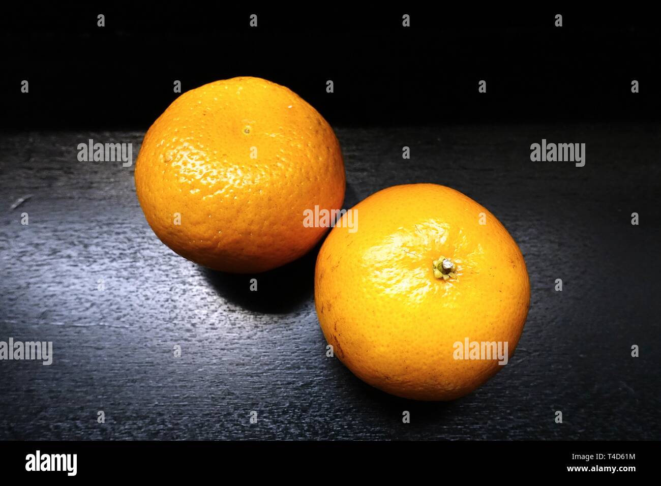 Two fresh oranges on shiny black background. Stock Photo
