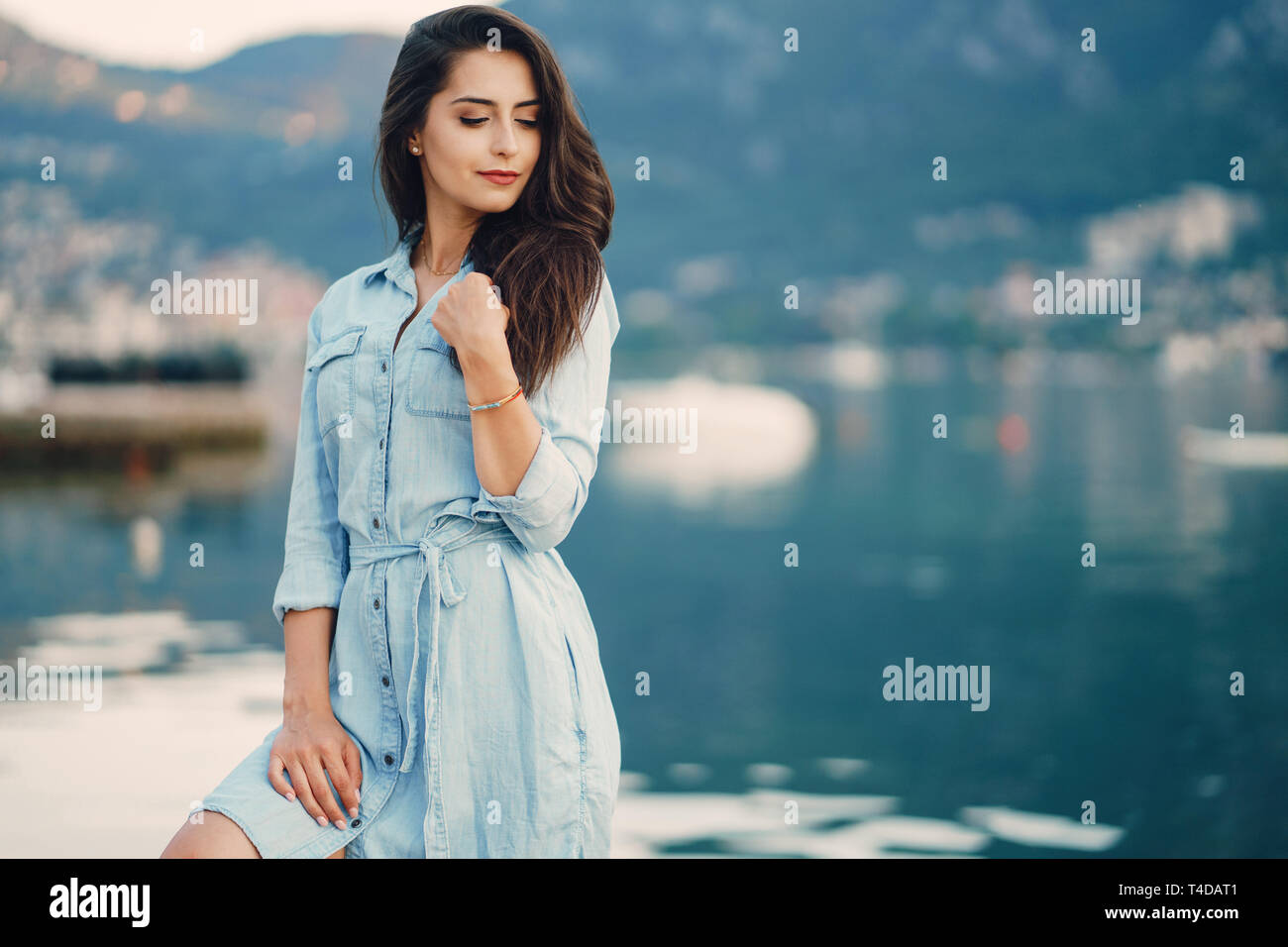 A beautiful young girl in a blue dress standing near water Stock Photo ...