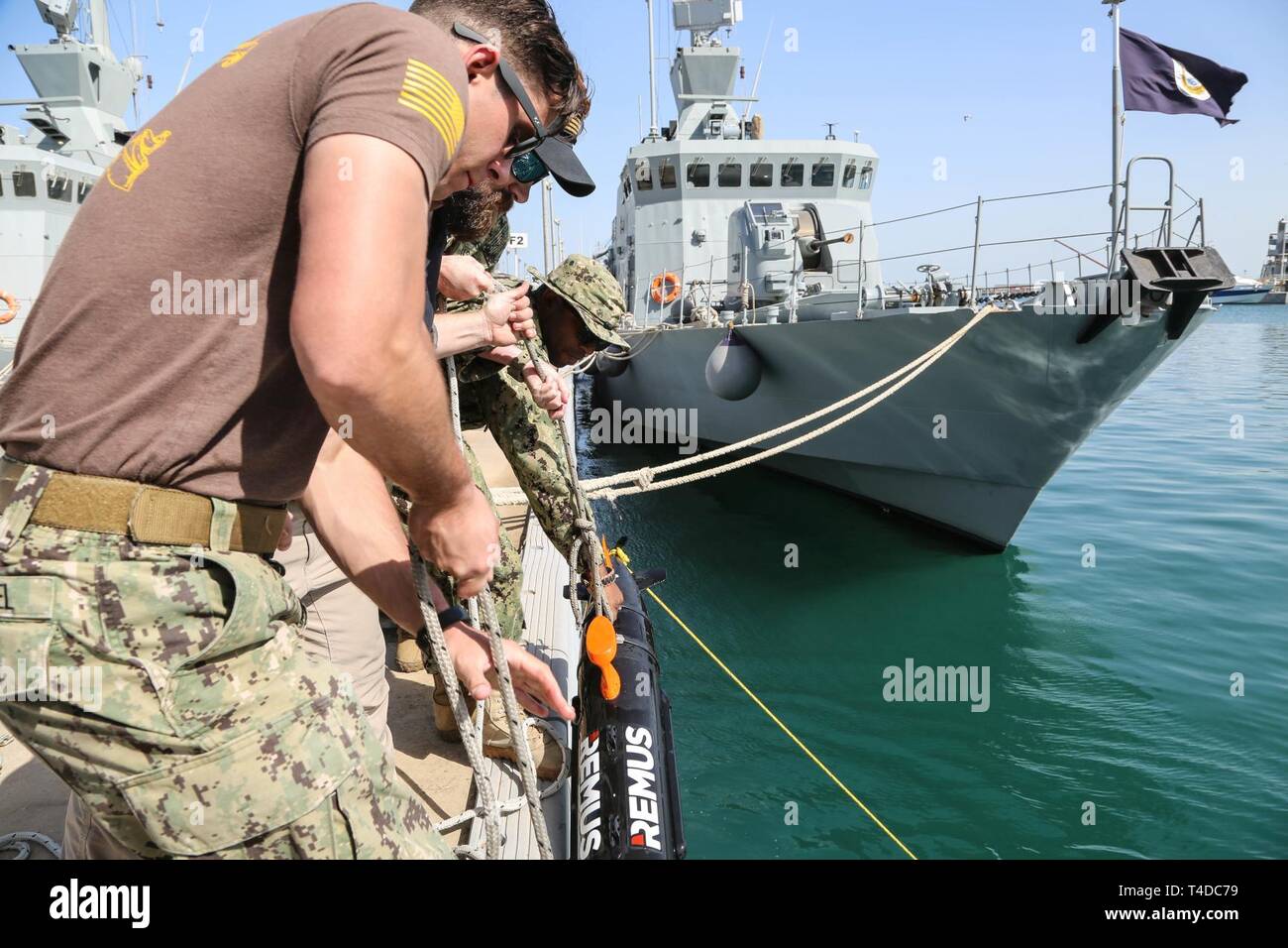 KUWAIT (March. 18, 2019) U.S. Navy Mineman 3rd Class Kody Manuel, left, and Aviation Aerographer 2nd Class Robert Wilcox remove the Remus 100, side scan sonar, after a successful clearing operation during exercise Eager Response 19. Eager Response 19 is a bilateral explosive ordnance and mine countermeasures exercise between the U.S. Navy and the Kuwait Navel Forces, allowing both nations to share knowledge and experiences to enhance mutual maritime capabilities and interoperability. Stock Photo