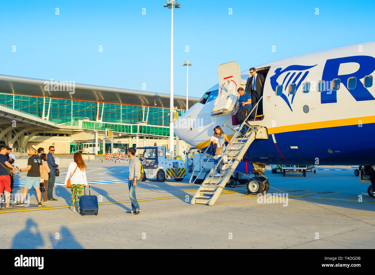 PORTO, PORTUGAL - MAY 24, 2017: Passengers leaving airplane by ladder, glass facade of airport in background Stock Photo