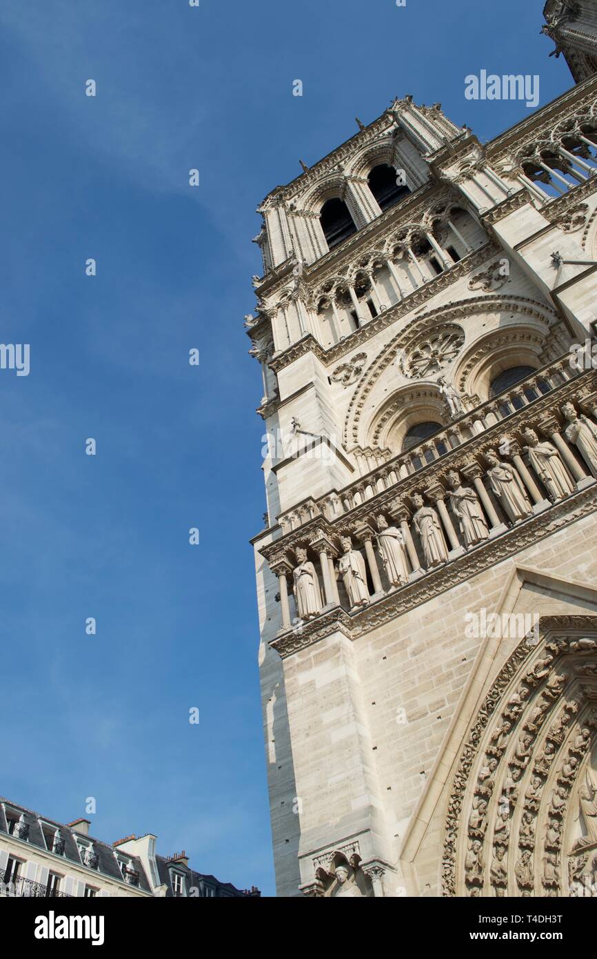 Looking up dramatically at Notre Dame Cathedral (Paris, France). Stone bell tower contrasting against bright blue sky. Stock Photo