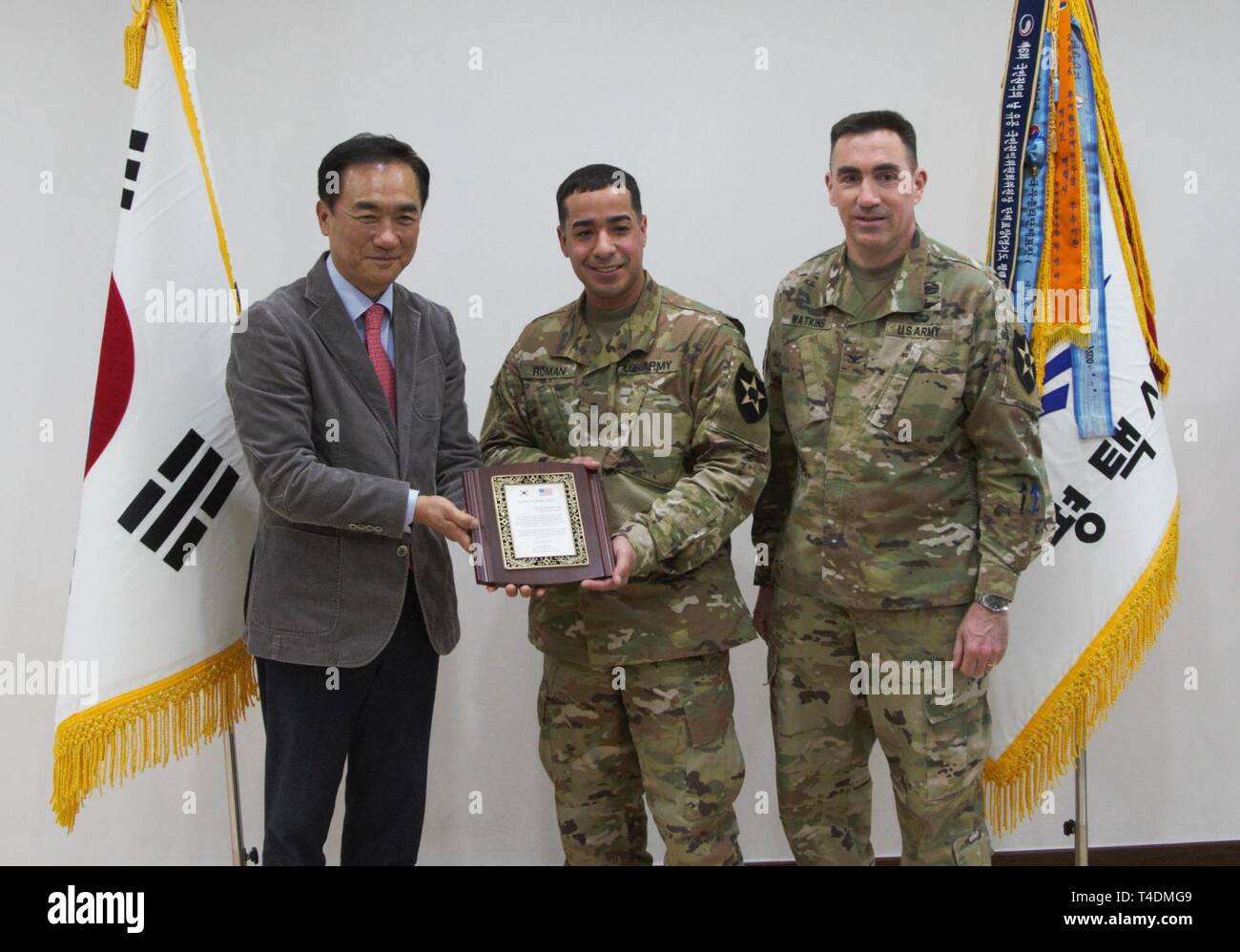 Pyeongtaek City Mayor Jung, Jang-Seon presents Spc. Jonathan Roman Rios, avionics and survivability equipment repairer, 602nd Aviation Support Battalion, 2nd Combat Aviation Brigade, 2nd Infantry Division/ROK-U.S. Combined Division a plaque of appreciation during a ceremony at Pyeongtaek City Hall, March 28. Rios demonstrated great selflessness when he protected two local community members, an elderly woman and small child, from an unchained, aggressive dog. Col. Brian T .Watkins, commander, 2CAB, right, and other Talon leadership also attended the ceremony. Stock Photo