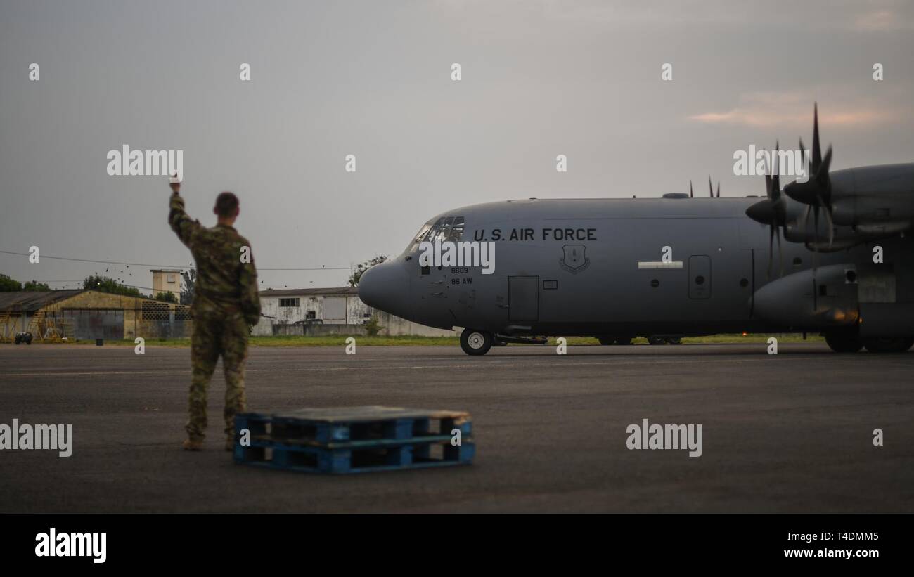 U.S. Air Force Capt. Matthew Oesterlec, a pilot assigned to the 75th Expeditionary Airlift Squadron, Combined Joint Task Force-Horn of Africa (CJTF-HOA), signals a C-130J Hercules departing Maputo International Airport, Mozambique, April 1, 2019, for the U.S. Department of Defense’s (DoD) relief effort in the Republic of Mozambique and surrounding areas following Cyclone Idai. Teams from CJTF-HOA, which is leading DoD support to relief efforts in Mozambique, began immediate preparation to respond following a call for assistance from the U.S. Agency for International Development’s Disaster Assi Stock Photo