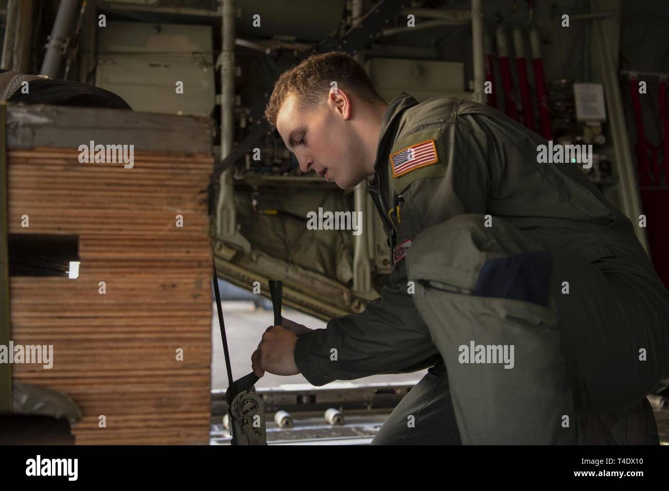 Airman 1st Class Matthew Pfeffer, 36th Airlift Squadron C-130J loadmaster, secures a low-cost low- altitude bundle during the Yokota C-130J Rodeo at Yokota Air Base, Japan, March 22, 2019. The flight, airdrop, and offload were a part of the Rodeo competition in which pilots and loadmasters are graded on their ability to execute their skillsets both accurately and expeditiously. Stock Photo