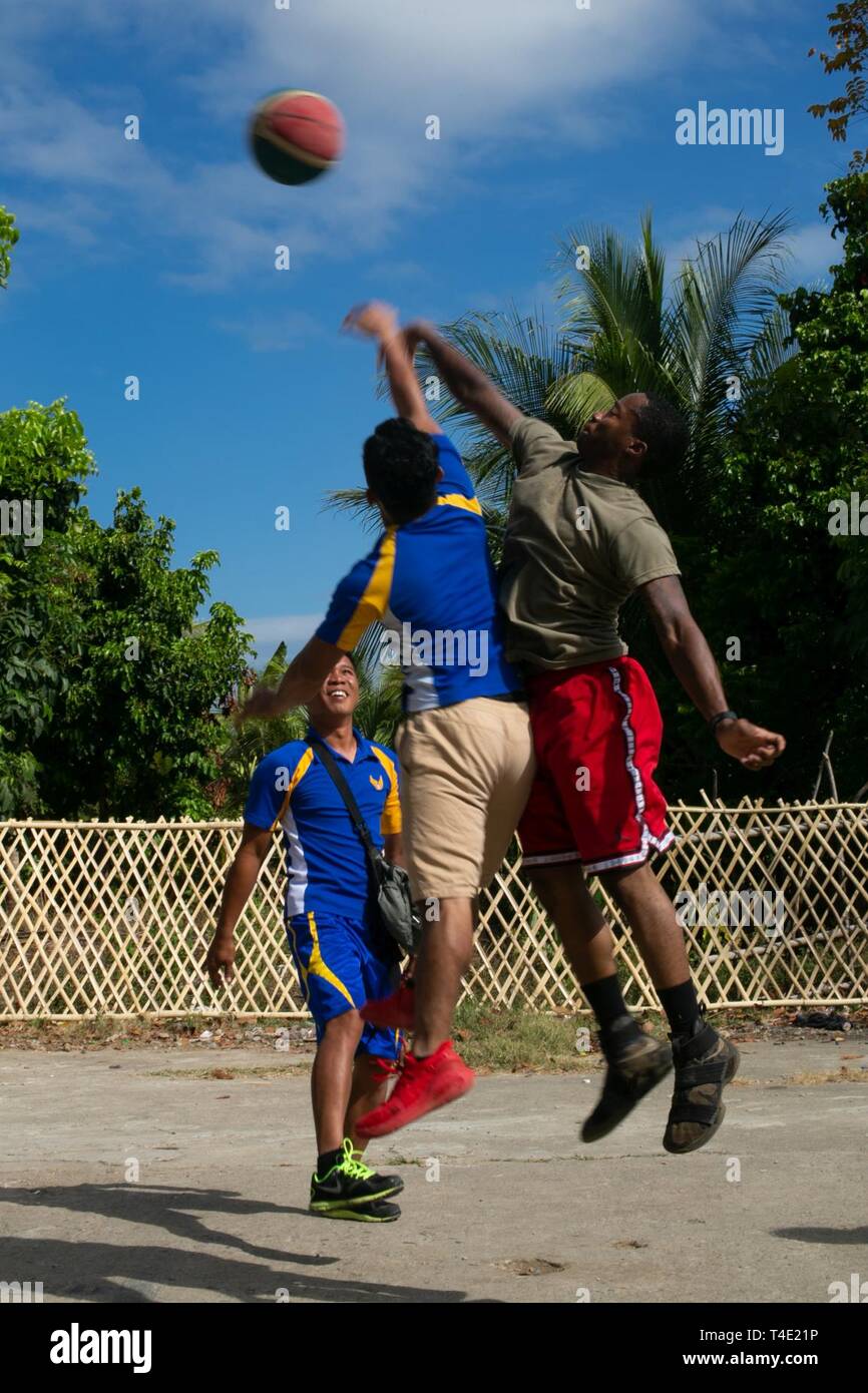U.S. Army Pfc. Cory Lee and Philippine Airman 2nd Class Ricky Batuigas jump  to tip the ball during a game of basketball as part of a community  relations event during Exercise Balikatan