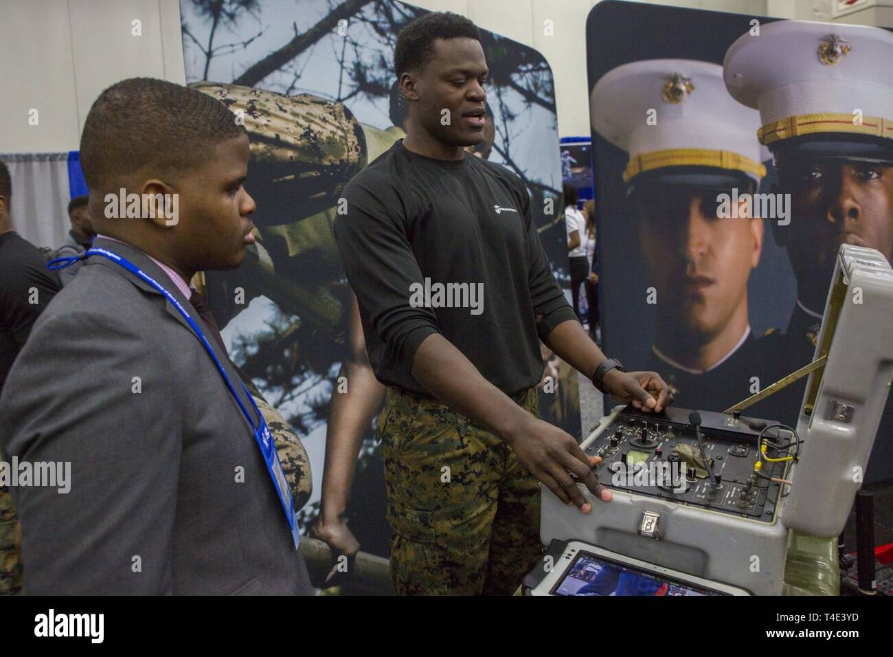 Marine Staff Sgt. Steven Bellamy, an explosive ordnance disposal technician with 2nd EOD Company, 8th Engineer Support Battalion, explains how to control EOD robots to Morayooluwa Ogunsina, a sophomore at Illinois Institute of Technology, during a National Society of Black Engineers conference career fair in Detroit, Michigan, March 29, 2019. NSBE is holding its 45th annual national convention consisting of various programs and workshops that are designed to benefit grade school, collegiate, technical, professional and international attendees and the U.S. Marine Corps is a partner organization Stock Photo