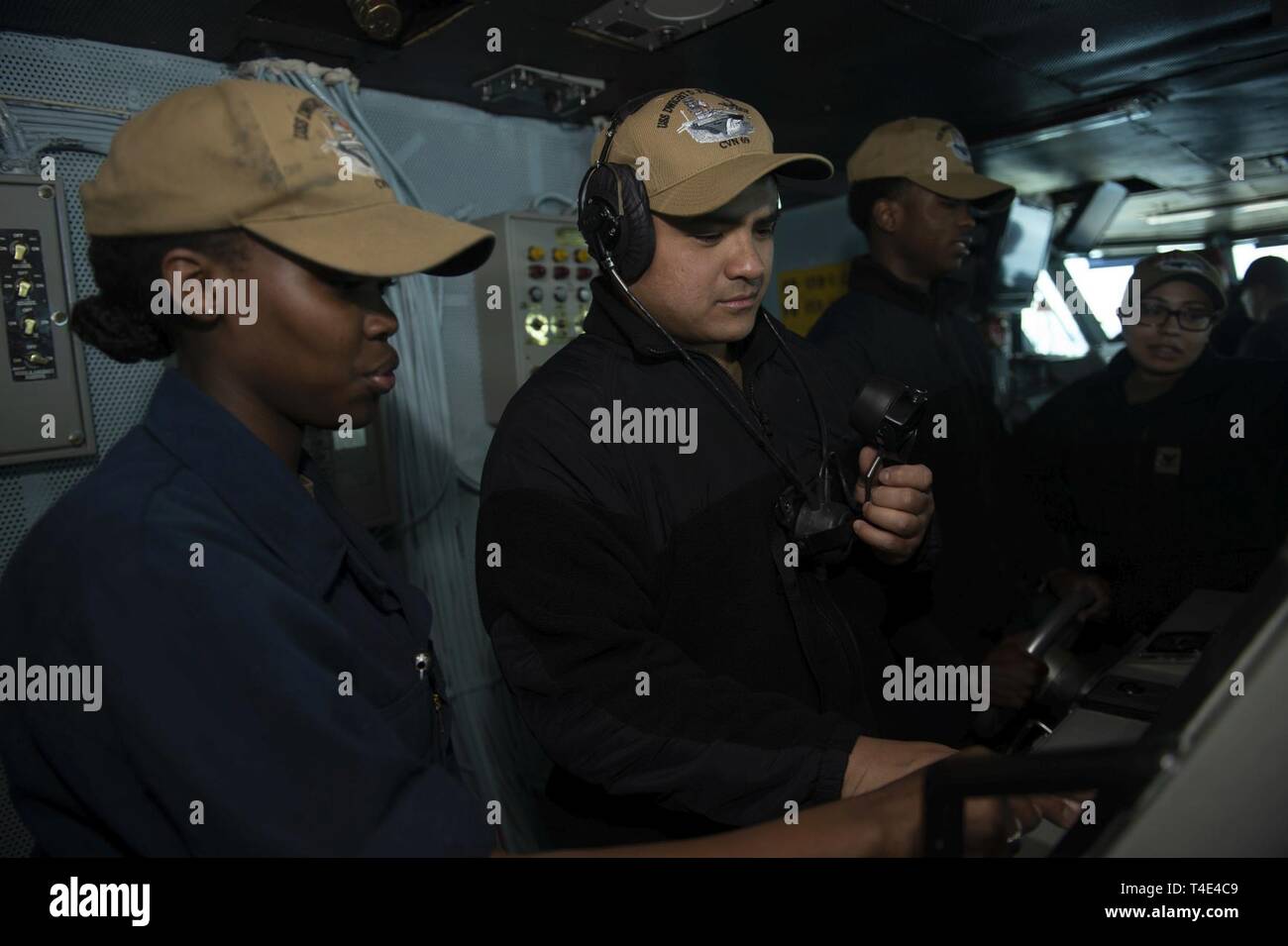 ATLANTIC OCEAN (March 29, 2019) Boatswain's Mate Seaman Elenoir Kosgei, left, from Greensborough, N.C., trains Seaman Jonathan Gancaycos, from Oakland Calif., on manning the helm on the bridge aboard the aircraft carrier USS Dwight D. Eisenhower (CVN 69). Ike is underway conducting sea trials during the final portion of a Planned Incremental Availability (PIA) as part of the maintenance phase of the Optimized Fleet Response Plan (OFRP). Stock Photo