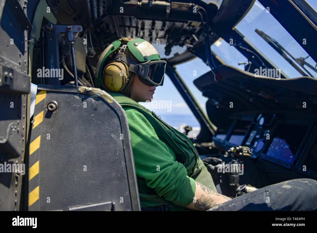 SOUTH CHINA SEA (March 29, 2019) -  Airman Alexandra Lucas, from Greensborough, N.C., prepares to taxi an MH-60S Sea Hawk assigned to Helicopter Sea Combat Squadron (HSC) 25 on the amphibious assault ship USS Wasp (LHD 1). Wasp, flagship of Wasp Amphibious Ready Group, is operating in the Indo-Pacific region to enhance interoperability with partners and serve as a lethal, ready-response force for any type of contingency. Stock Photo