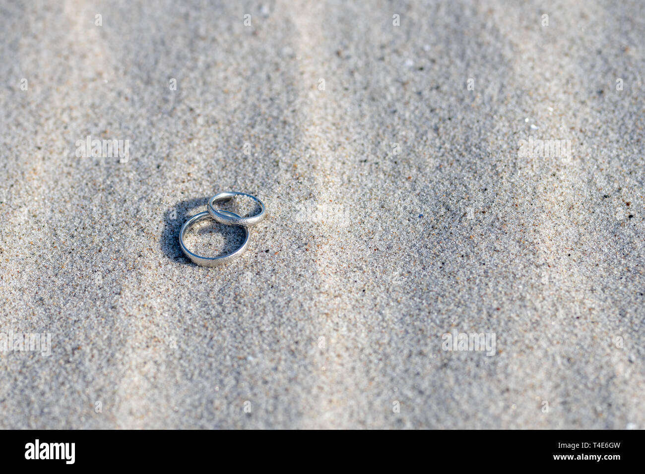 a pair of Wedding Rings on tropical beach with beautiful carvings Stock Photo