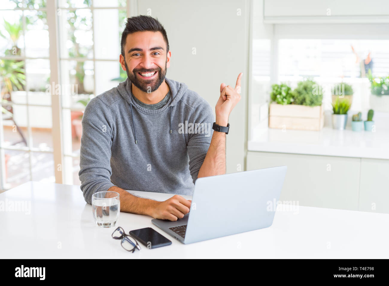 Hispanic Man Using Computer Handsome hispanic man working using computer laptop very happy pointing ...
