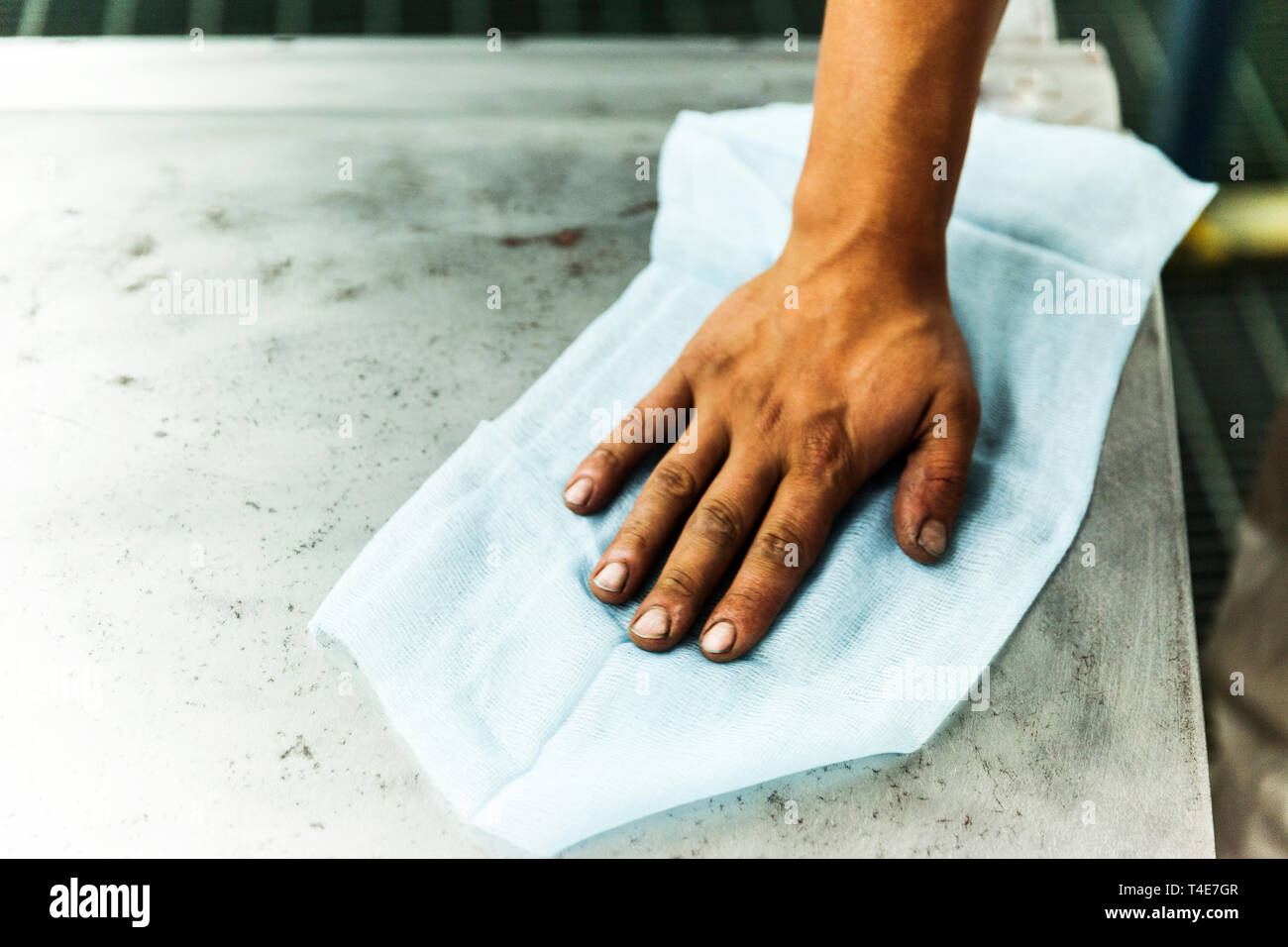Rubbing down steel surface with blue cloth Stock Photo Alamy
