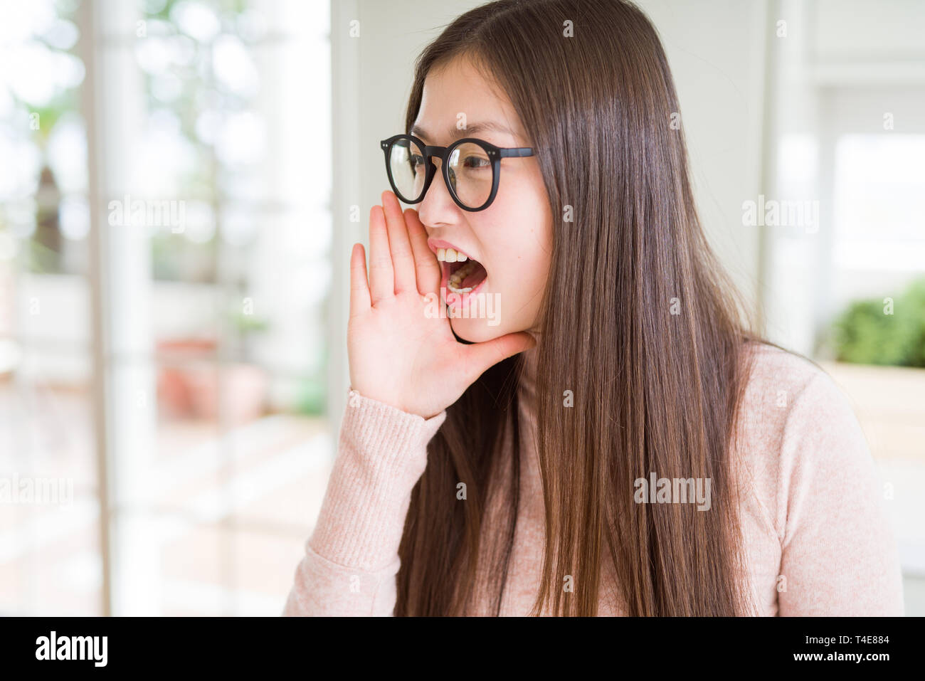 Beautiful Asian woman wearing glasses shouting and screaming loud to ...