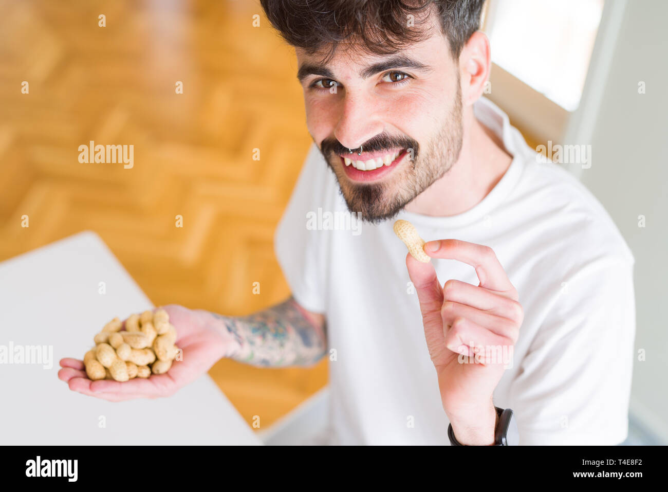 Young man eating peanuts, close up of hand with a bunch of healthy nuts Stock Photo