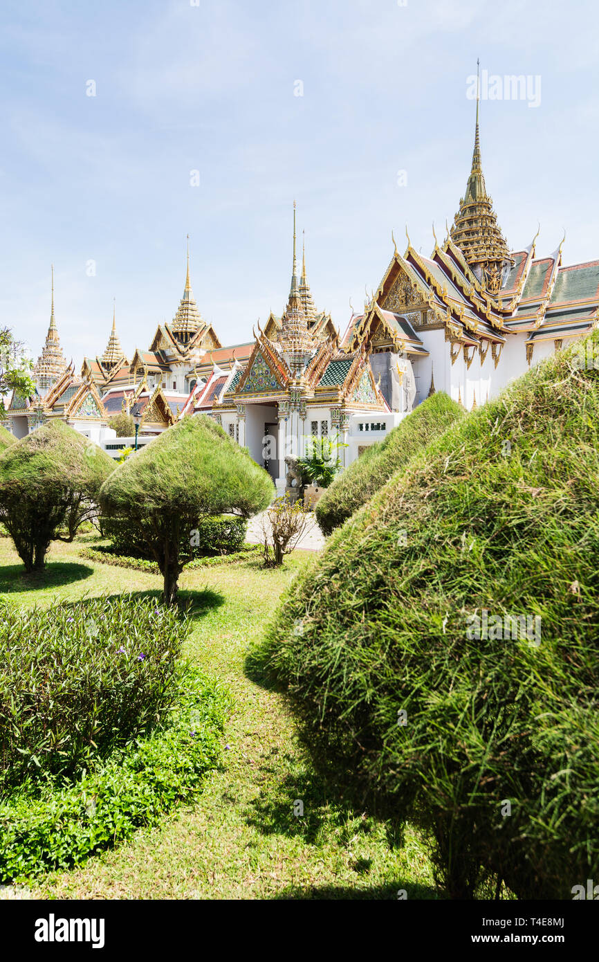 BANGKOK, THAILAND - MARCH 2019: View over Grand Palace and Chakri Maha Prasat hall through the trees and bushes at sunny day Stock Photo