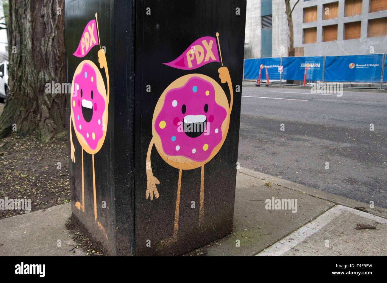 A pair of smiling cartoon doughnuts can be seen from a sidewalk in downtown Portland, OR. Stock Photo