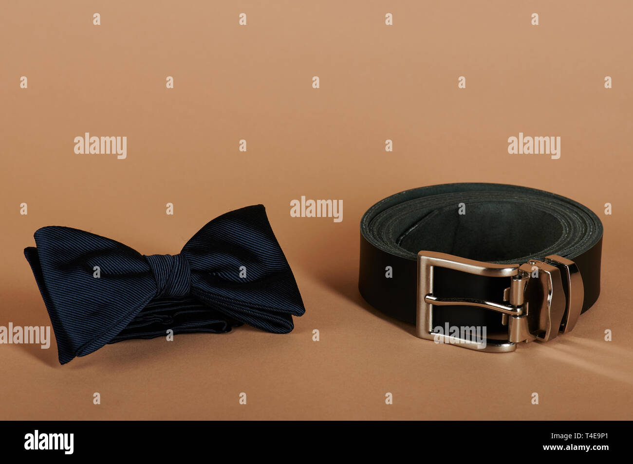 Blue bow tie and black belt on beige background close up view Stock Photo