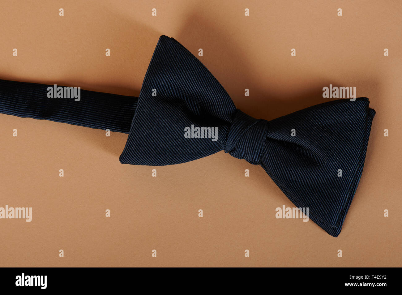 One blue color bow tie on beige color background Stock Photo