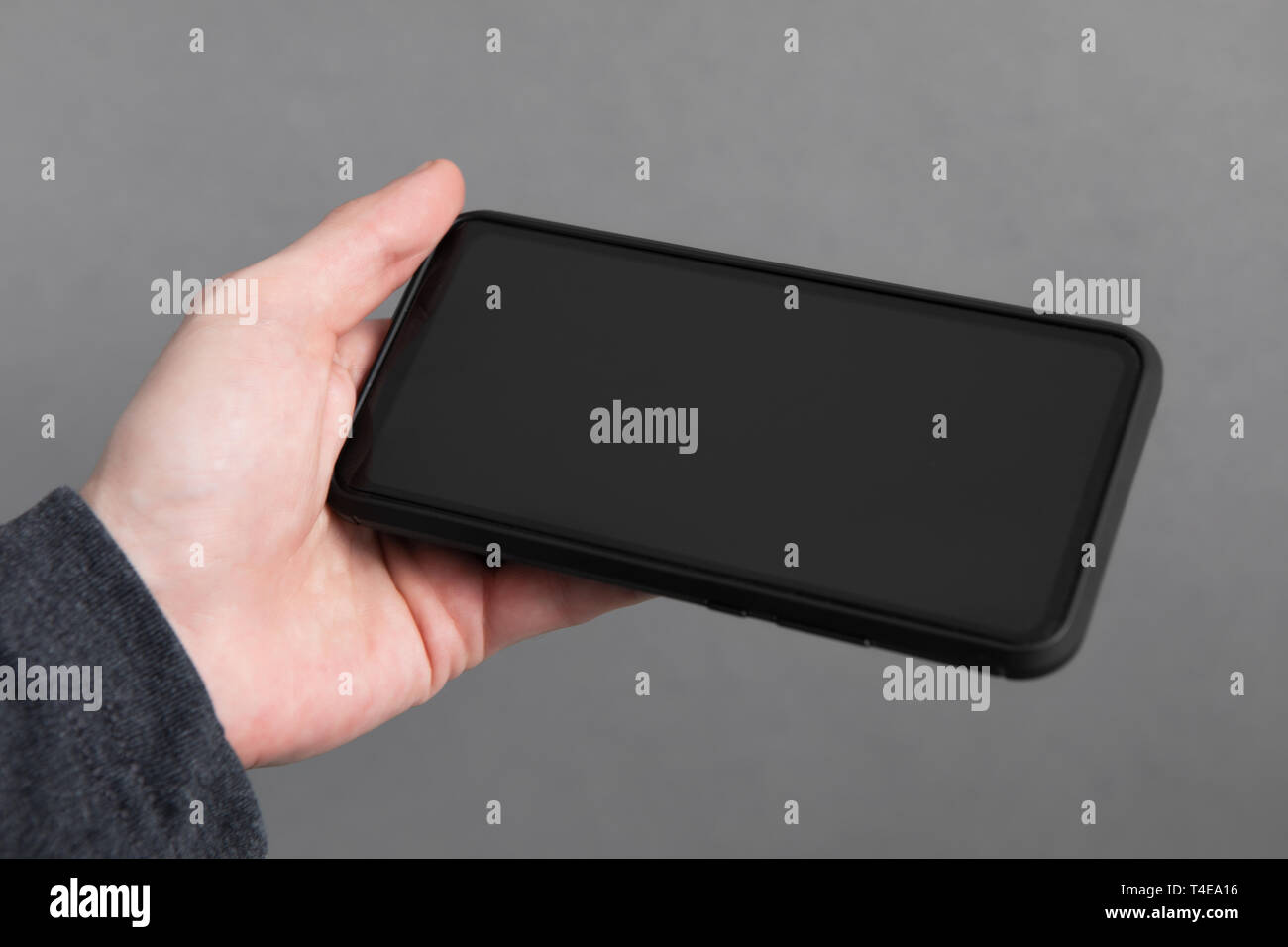 Mans hand holding black screen mobile phone Stock Photo