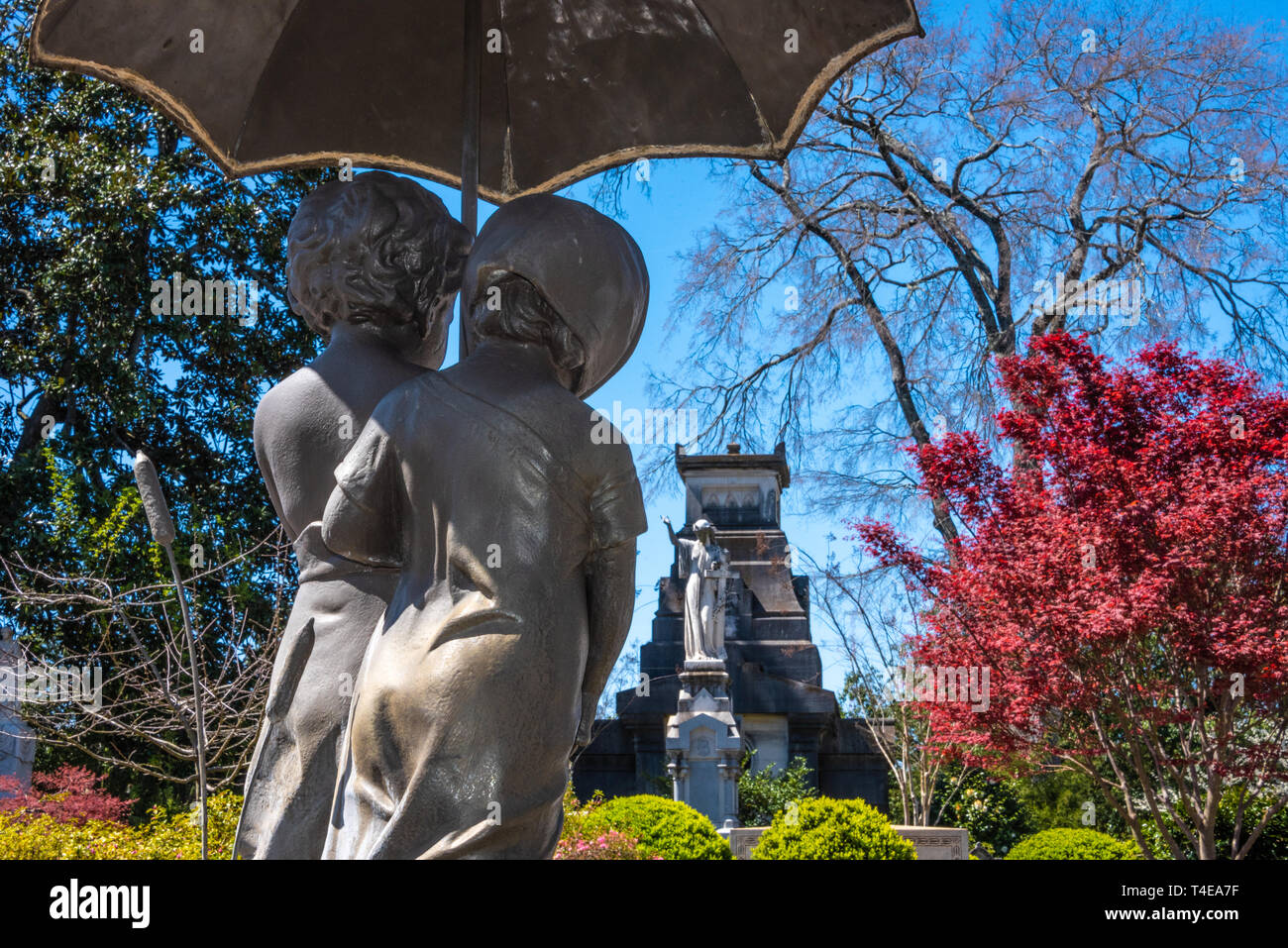 Cast iron bronze-finished sculpture, titled 'Out in the Rain,' of children under an umbrella at Historic Oakland Cemetery in Atlanta, Georgia. (USA) Stock Photo