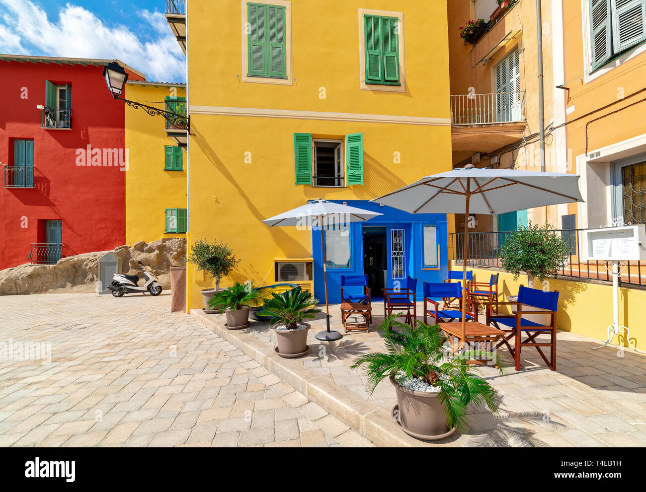 Small outdoor restaurant and colorful houses in Menton, France. Stock Photo