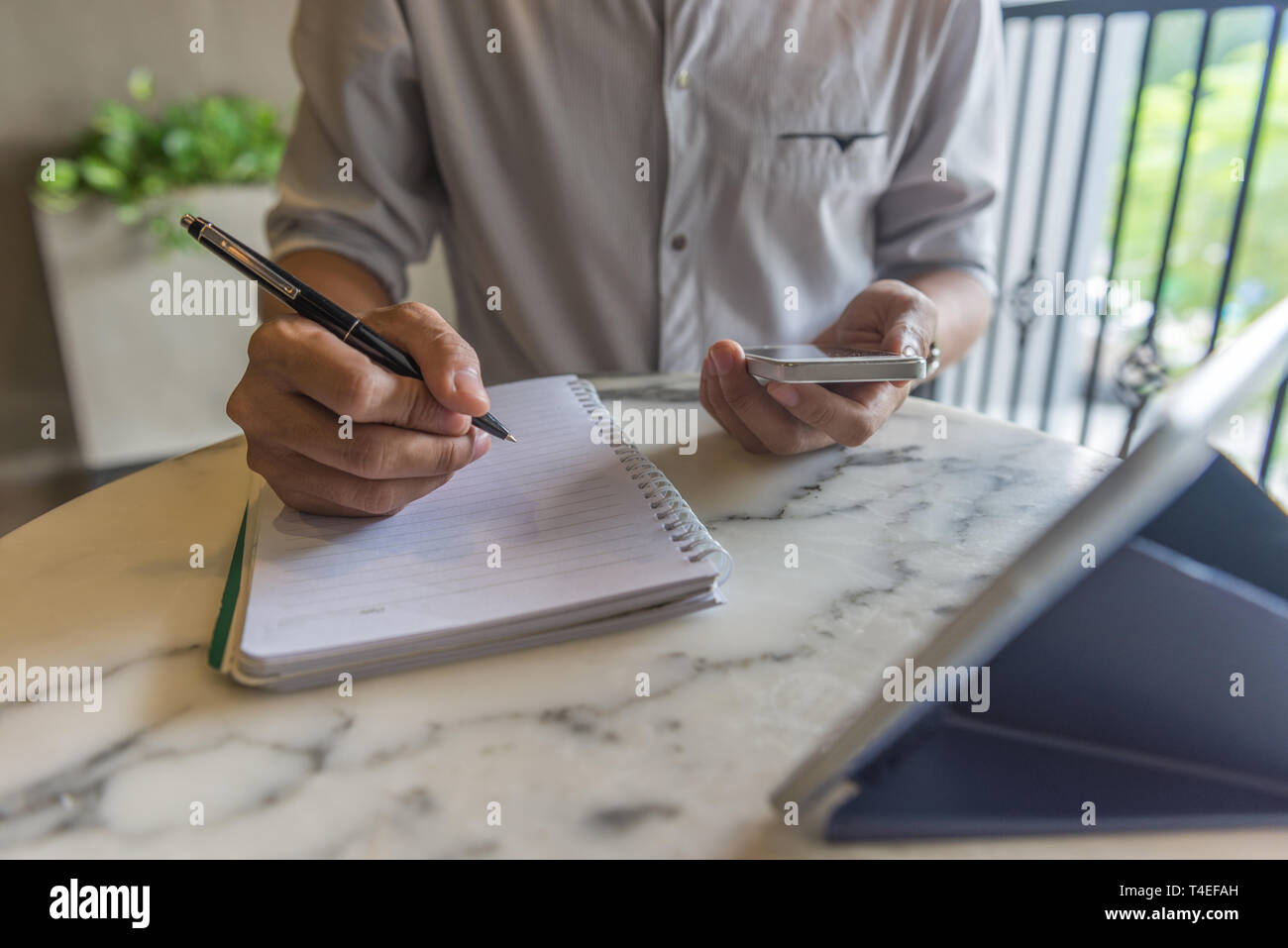 Dig Into Notes Young freelancer using smartphone and writing into note Stock Photo - Alamy
