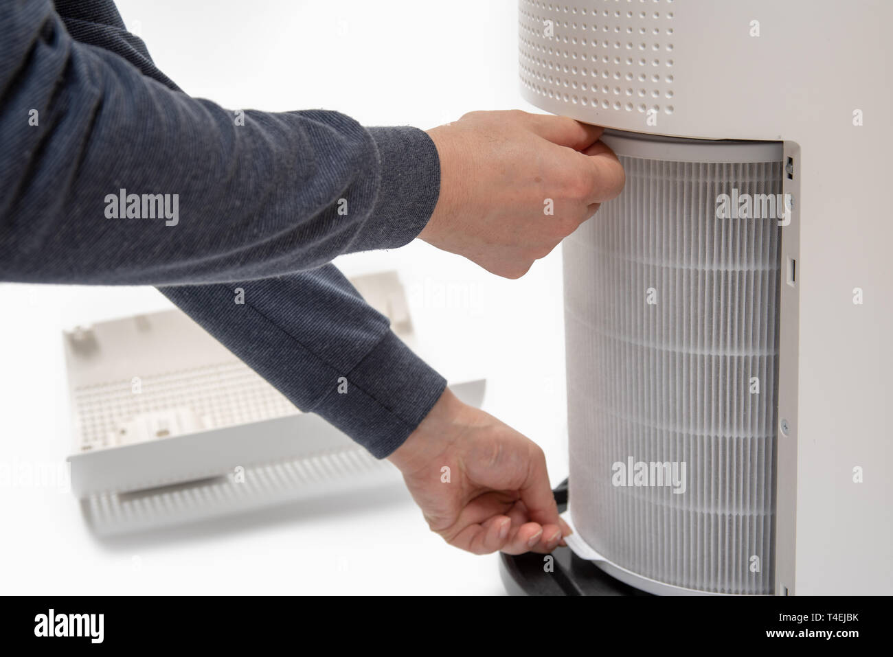 A man's hand turning an air purifier's filter into a new one. Stock Photo