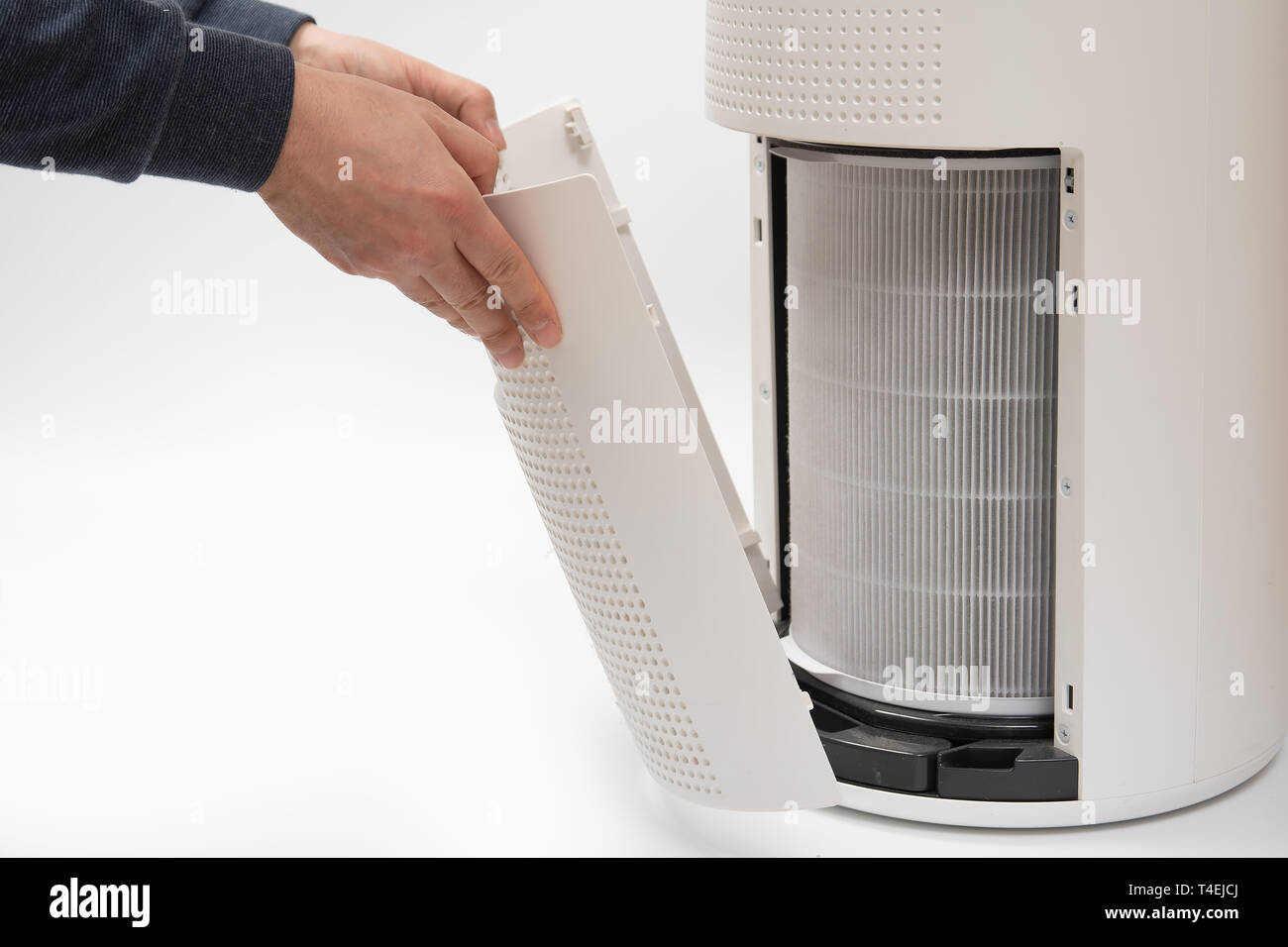 A man's hand turning an air purifier's filter into a new one. Stock Photo
