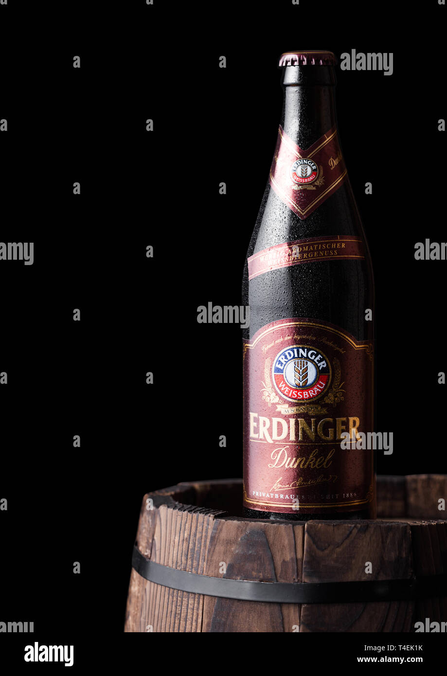 LONDON, UK - JULY 28, 2018: Bottle of Erdinger Dunkel beer on a wooden barrel and black background.Erdinger is the product of the world's largest whea Stock Photo